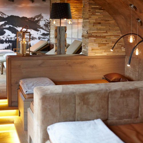 Hotel Sonnenhof Gemütlicher Wellnessraum mit Holzdecke, Leuchten und Bergpanorama an der Wand