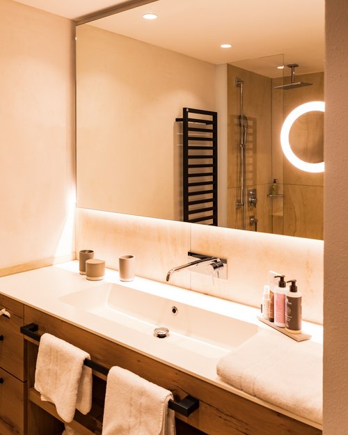 Hotel Sonnenhof Modernes Badezimmer mit großem Spiegel, Waschbecken und Handtüchern