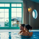 Hotel Sonnenhof Paar entspannt im Innenpool mit großer Fensterfront und Bergblick