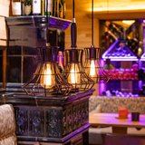 Hotel Sonnenhof Warme Hängeleuchten über Holztisch in gemütlicher Bar mit Flaschenregal