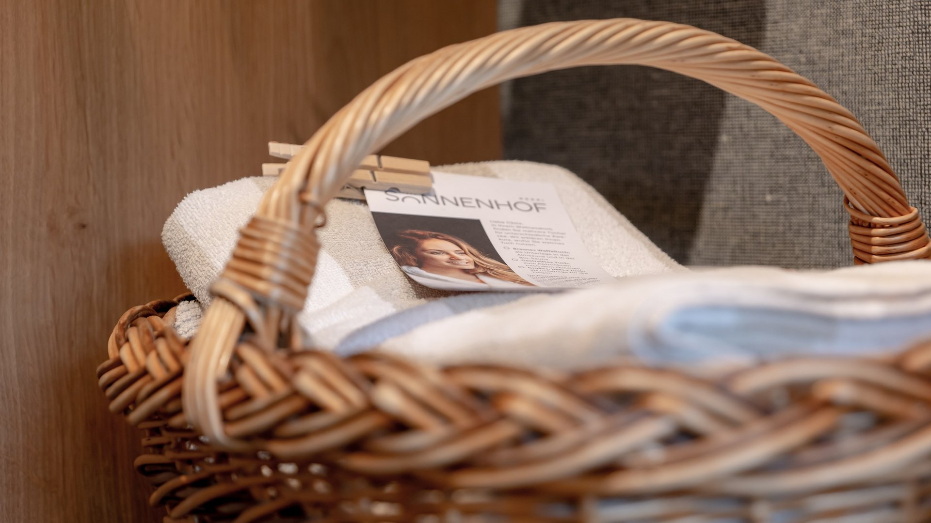 Hotel Sonnenhof Geflochtener Korb mit weißen Handtüchern und einer Karte mit Frauenbild
