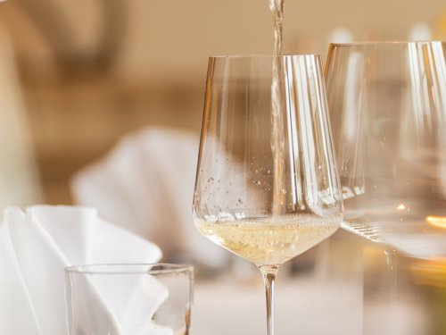 Hotel Sonnenhof Weißwein wird in ein Weinglas in einem eleganten Restaurant eingeschenkt
