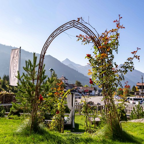 Hotel Sonnenhof Rosenbogen im Garten mit Bergpanorama und blauem Himmel im Hintergrund