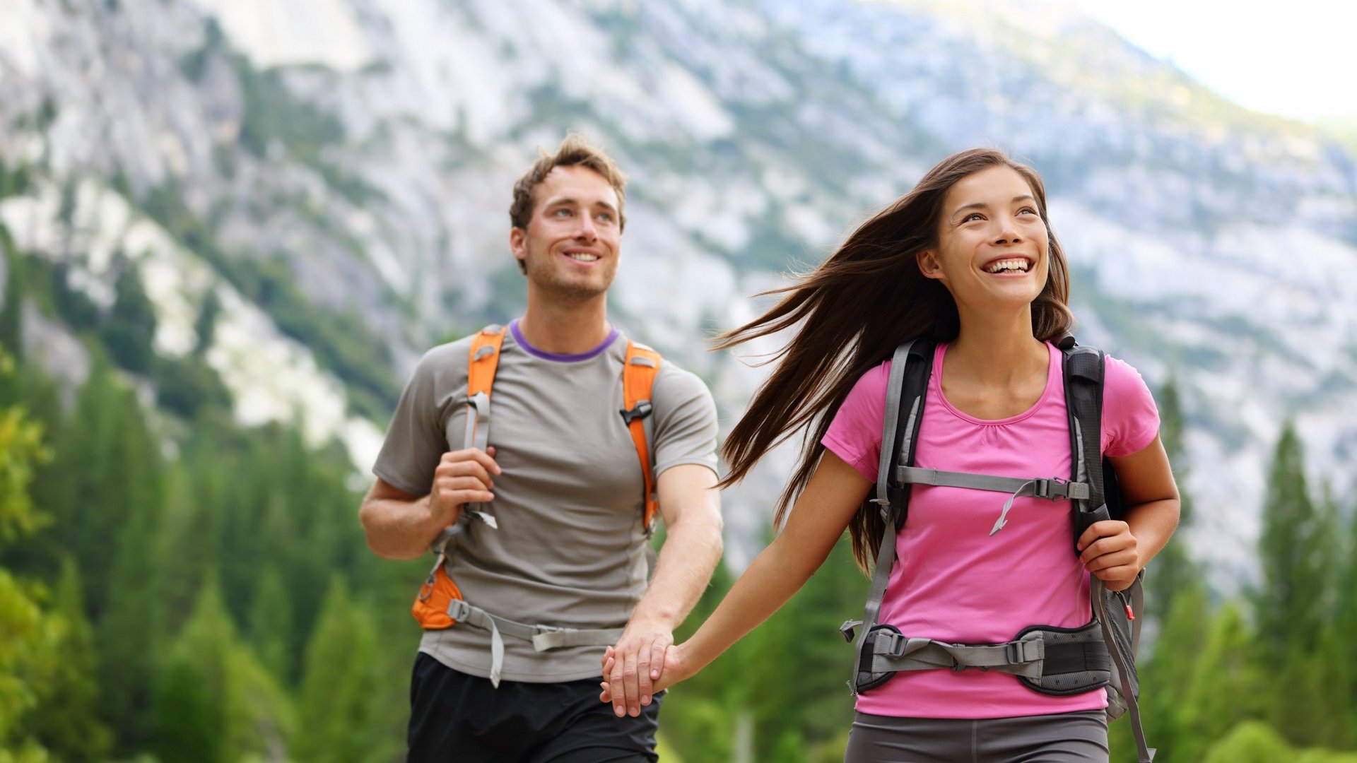 Hotel Sonnenhof Paar mit Rucksäcken beim Wandern in den Bergen hält Händchen und lächelt