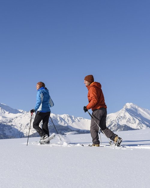 Hotel Sonnenhof Zwei Personen machen Schneeschuhwandern in den verschneiten Bergen bei klarem Himmel
