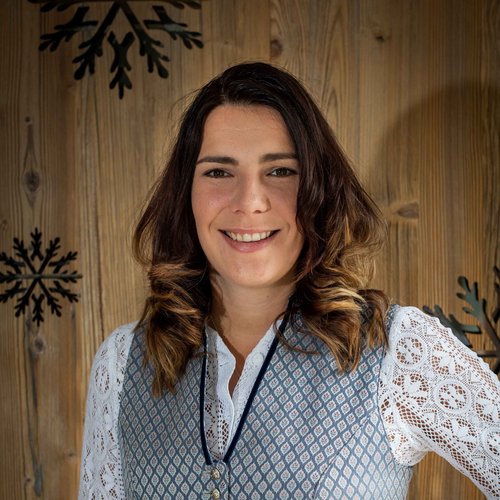 Hotel Sonnenhof Frau in traditioneller Tracht vor Holzwand mit Schneeflocken-Dekor