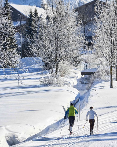 Hotel Sonnenhof Zwei Menschen beim Langlauf in verschneiter Landschaft mit Bergen im Hintergrund