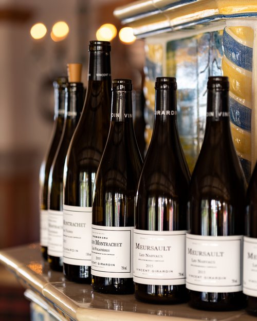 Hotel Sonnenhof Mehrere Weinflaschen mit weißen Etiketten auf einer verzierten Kachelablage