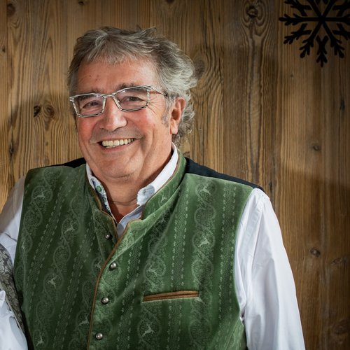 Hotel Sonnenhof Älteres Paar in traditioneller bayerischer Tracht vor Holzwand