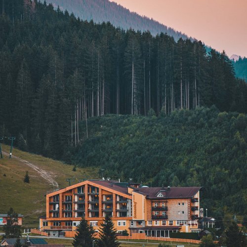 Hotel Sonnenhof Alpenhotel vor Nadelwald und Bergen bei Sonnenuntergang