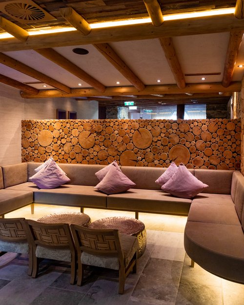 Hotel Sonnenhof Gemütliche Lounge mit Holzdecke, Sofas und Holzscheiben-Wanddesign