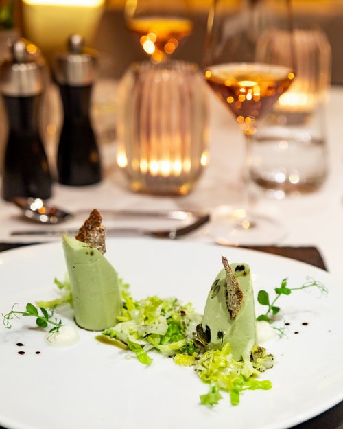 Hotel Sonnenhof Elegante Vorspeise mit grüner Creme, Salat und knusprigem Brot auf weißem Teller