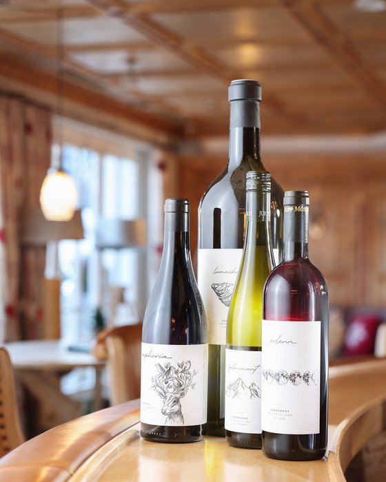 Hotel Sonnenhof Vier Weinflaschen mit eleganten Etiketten auf einer Holztheke in einem Restaurant