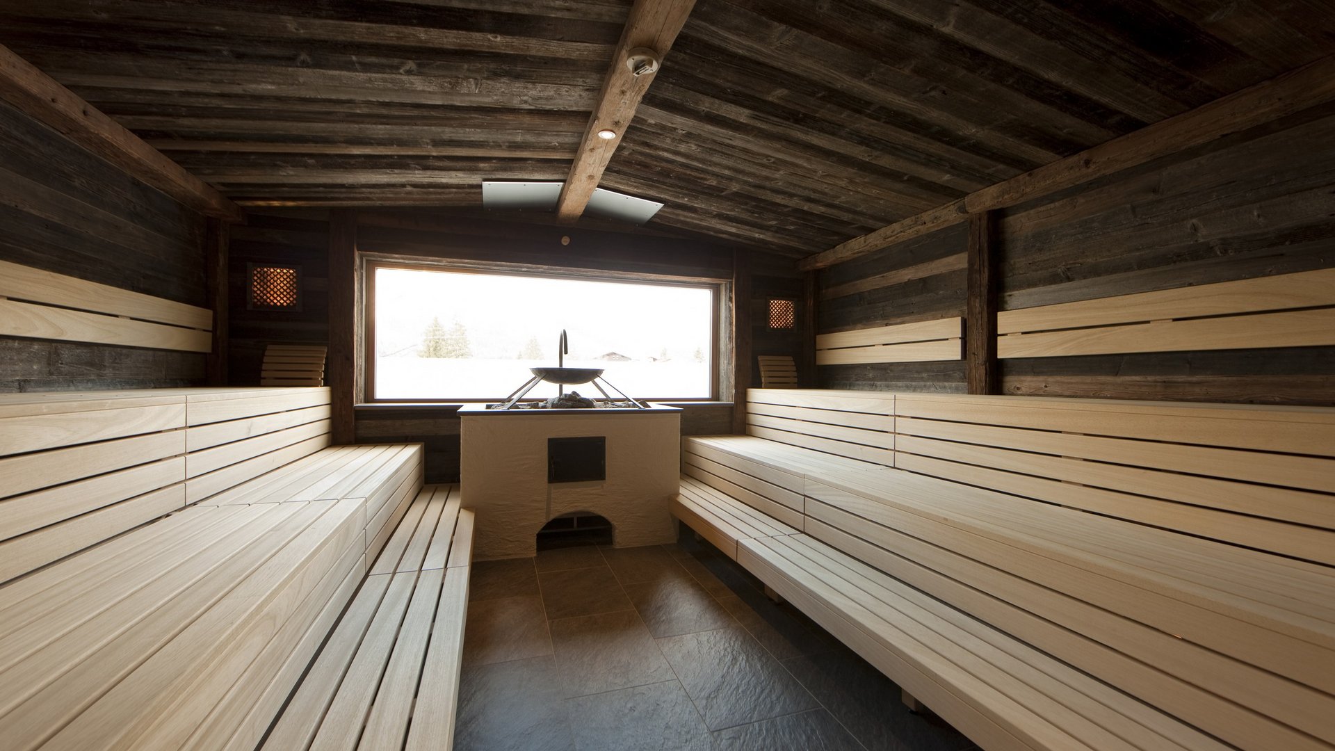 Hotel Sonnenhof Helle Holzsauna mit großen Sitzbänken und Fenster mit Außenaussicht