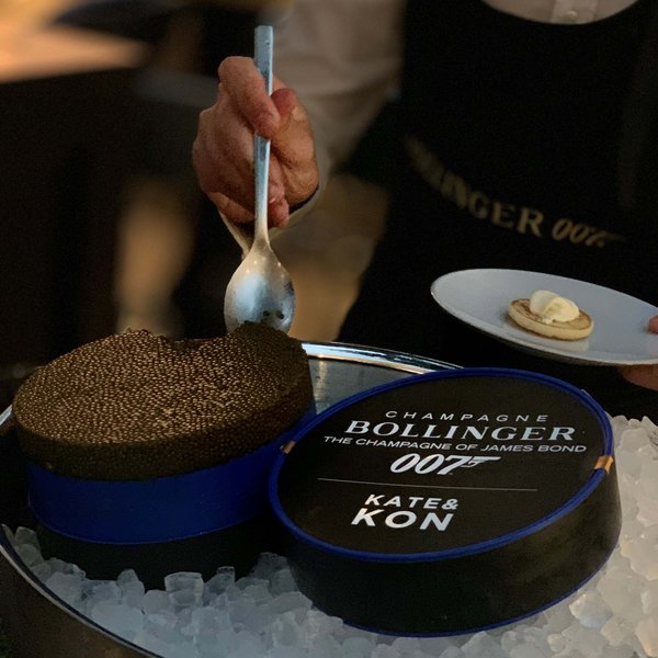 Hotel Sonnenhof Person schöpft Kaviar aus Dose auf Eis mit Teller und Brötchen