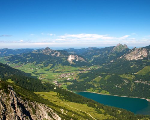 Hotel Sonnenhof Panoramablick auf Berge, Tal, See und Dorf unter klarem blauem Himmel