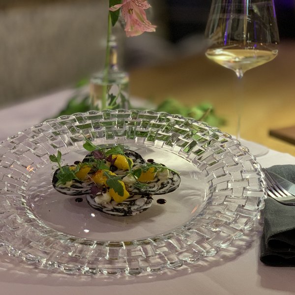 Hotel Sonnenhof Fein angerichtetes Gericht mit Garnitur auf transparentem Glassteller mit Besteck und Glas