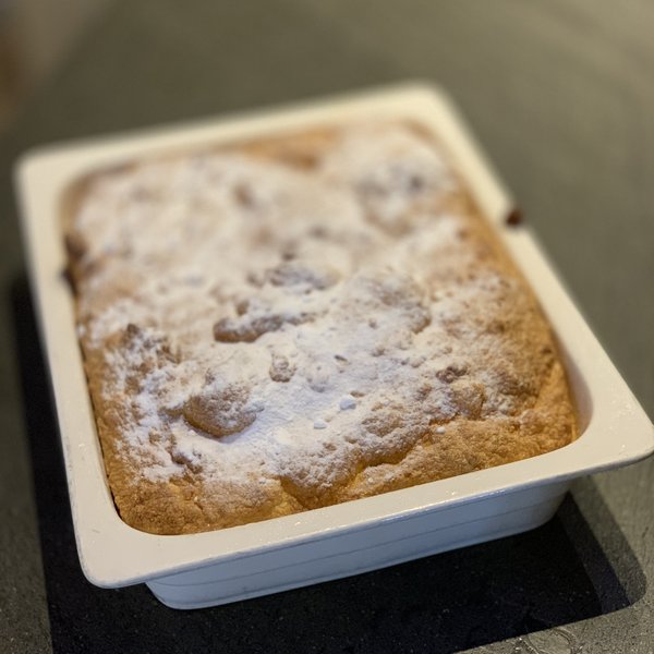 Hotel Sonnenhof Frischer gebackener Kuchen in weißer Backform mit Puderzucker bestreut