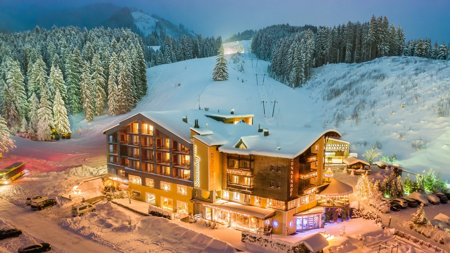 Hotel Sonnenhof Winterliches Hotel am Skihang mit beleuchteten Fenstern und verschneiten Bäumen