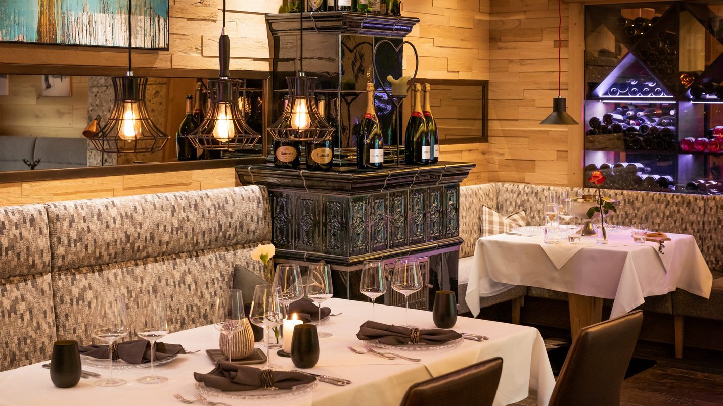 Hotel Sonnenhof Gemütliches Restaurant mit eingedeckten Tischen und Weinflaschen auf Kamin