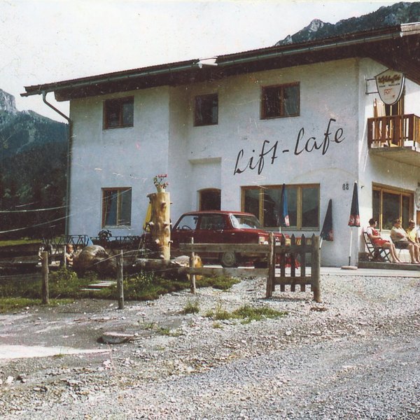 Hotel Sonnenhof Lift-Lafe Gebäude mit Bergen im Hintergrund und Personen auf der Terrasse