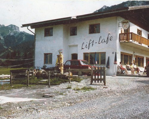 Hotel Sonnenhof Lift-Lafe Gebäude mit Bergen im Hintergrund und Personen auf der Terrasse
