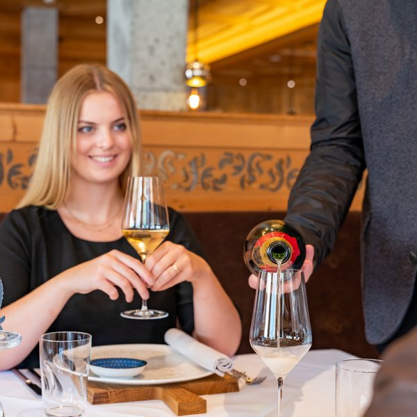 Hotel Sonnenhof Frau mit Weißweinglas im Restaurant während Kellner Wein einschenkt