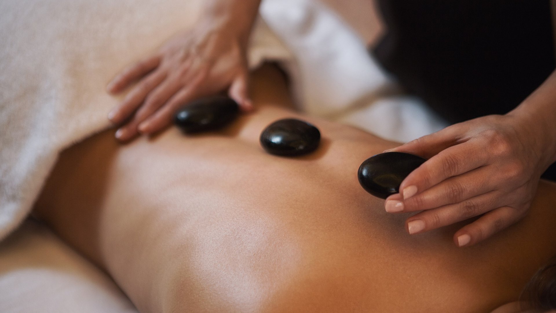 Hot-Stone-Massage mit Bergblick – Sky Spa im Sonnenhof Tirol, Grän Person erhält Hot-Stone-Massage auf nacktem Rücken