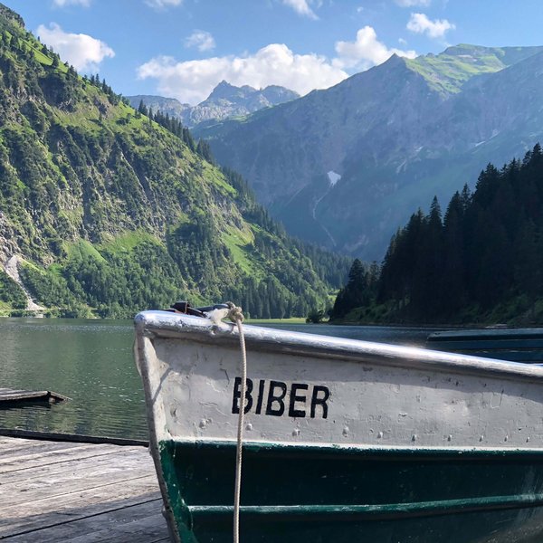Hotel Sonnenhof Boot Biber auf See mit grünen Bergen und blauem Himmel im Hintergrund