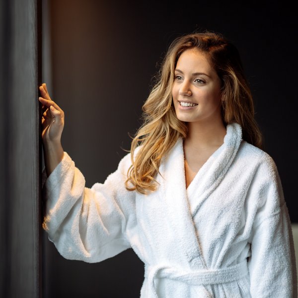 Hotel Sonnenhof Frau im weißen Bademantel, die lächelnd aus dem Fenster schaut