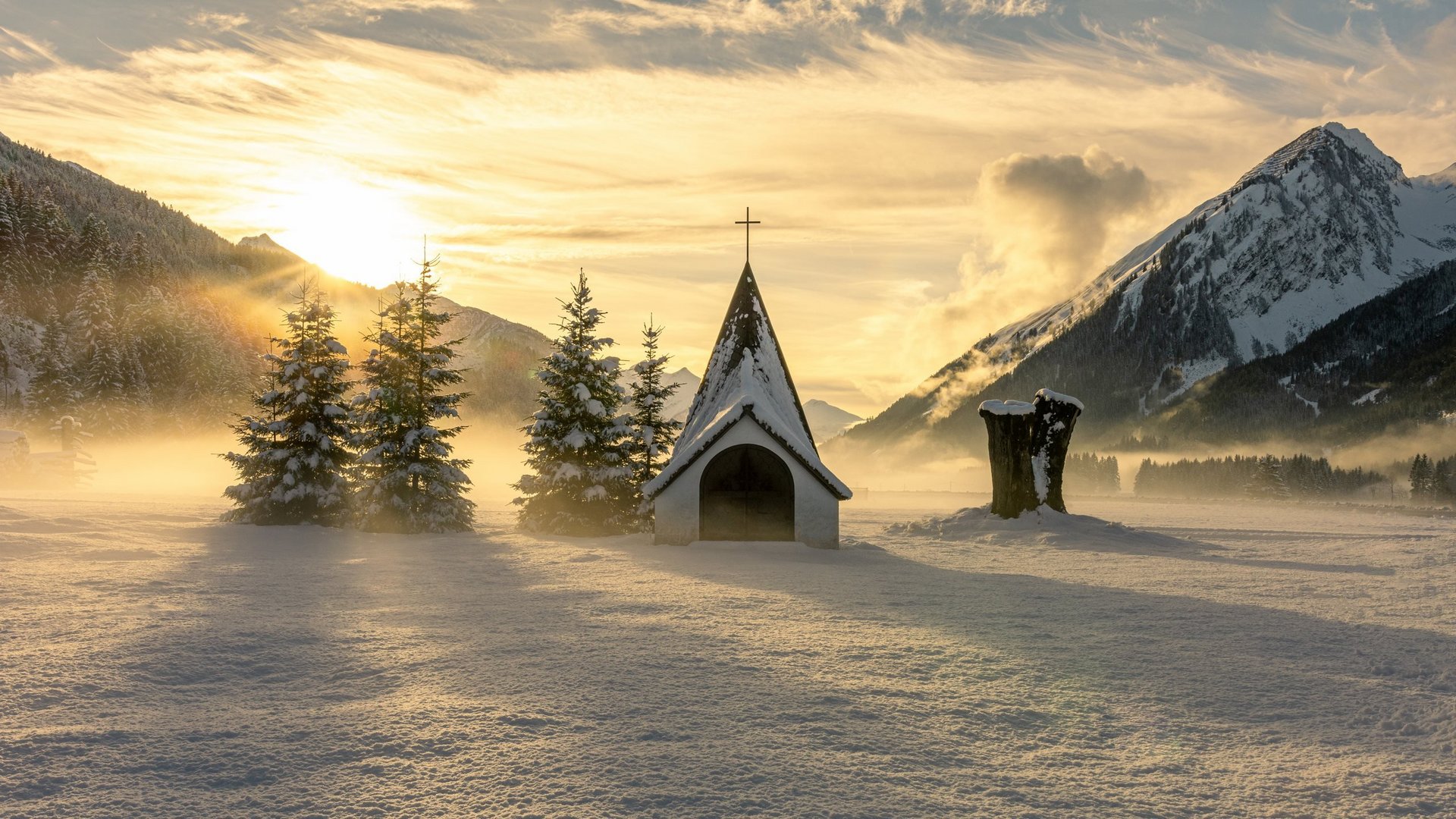 Hotel Sonnenhof Small chapel and snow-covered trees in a snowy mountain valley at sunrise