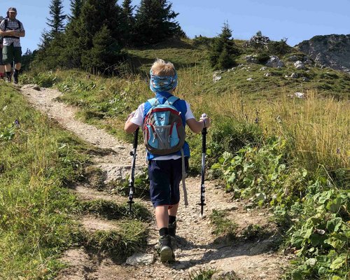 Hotel Sonnenhof Kind mit Wanderausrüstung wandert auf einem Pfad in bergiger Landschaft