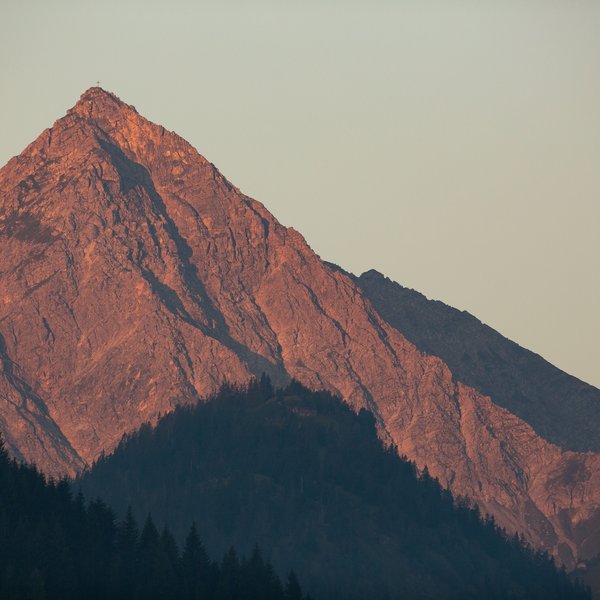 Hotel Sonnenhof Berggipfel im Sonnenuntergang mit Kreuz und Kirchenkreuz im Vordergrund