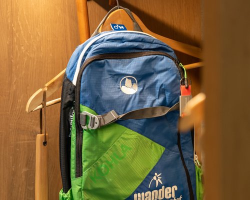 Hotel Sonnenhof Blauer und grüner Wanderrucksack hängt an einem Holzhaken in einem Schrank