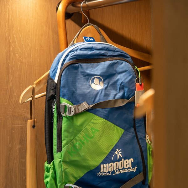 Hotel Sonnenhof Blauer und grüner Wanderrucksack hängt an einem Holzhaken in einem Schrank