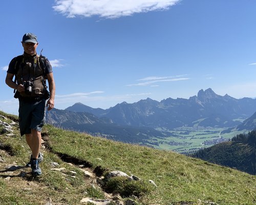 Hotel Sonnenhof Mann mit Kamera wandert auf Bergpfad mit Alpenpanorama im Hintergrund