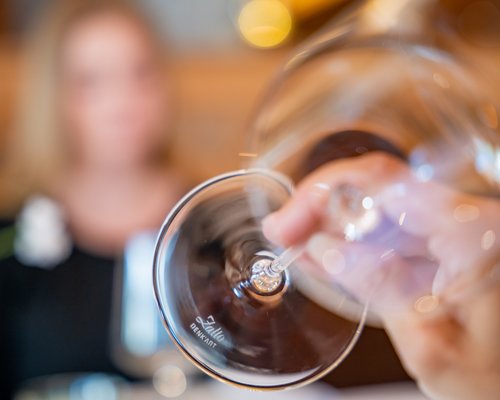 Hotel Sonnenhof Nahaufnahme eines leeren Weinglases mit verschwommener Person im Hintergrund